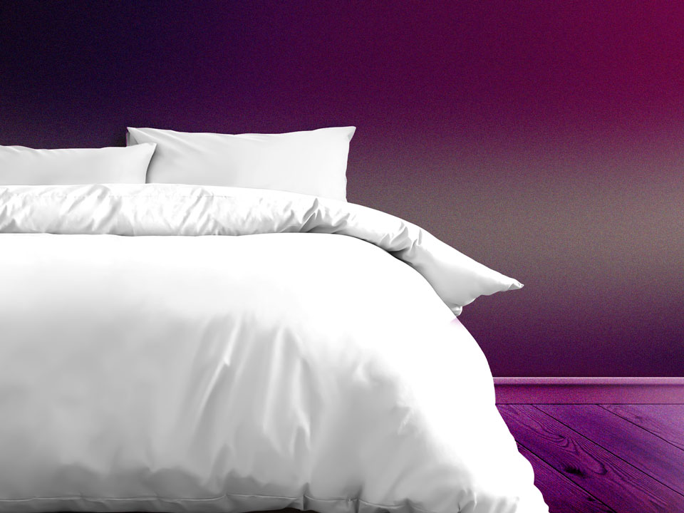 bed with white comforter on a purple background