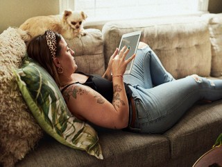 Woman laying on couch with dog and tablet